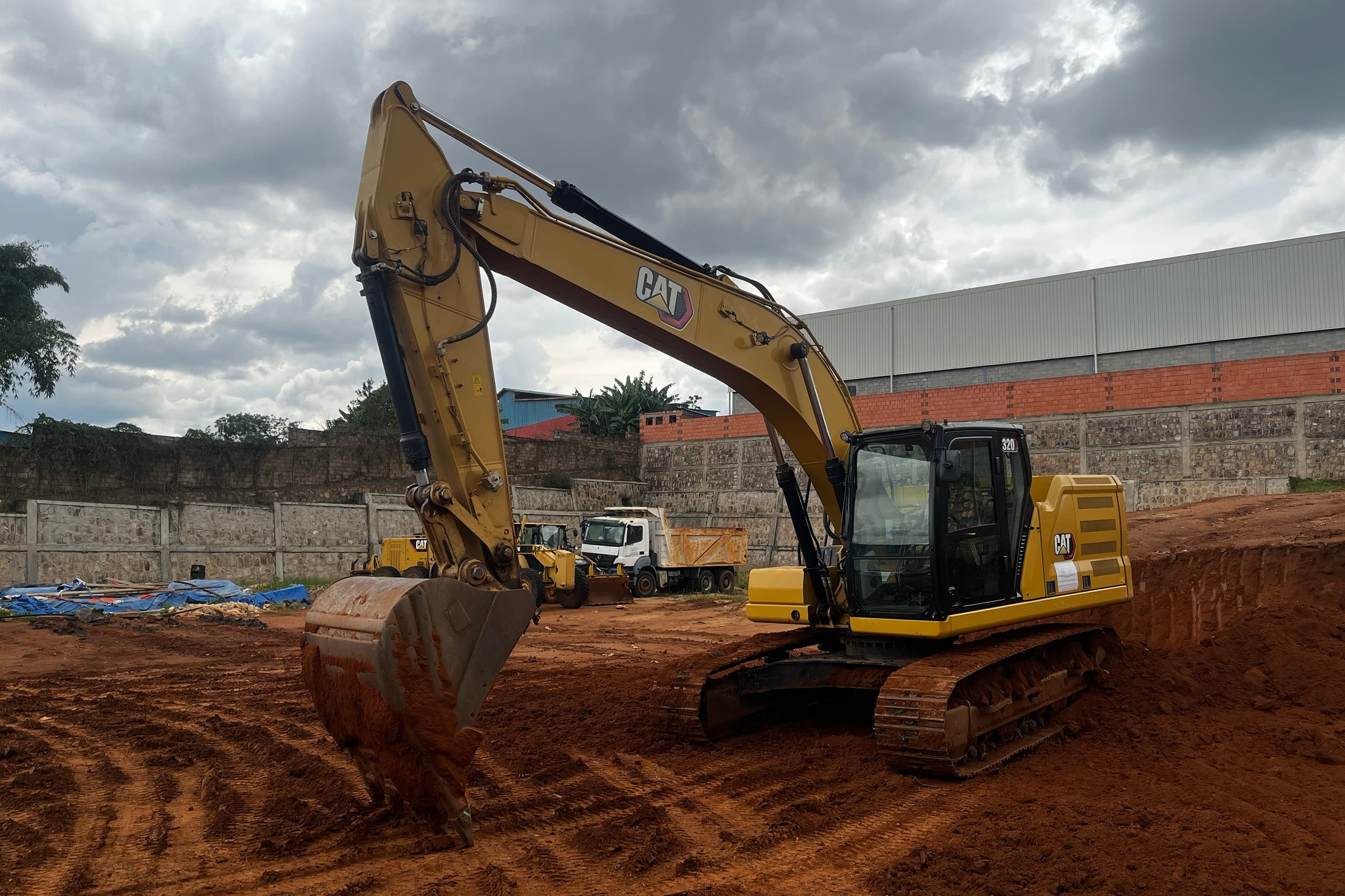 CAT excavator with raised arm against a dramatic sky